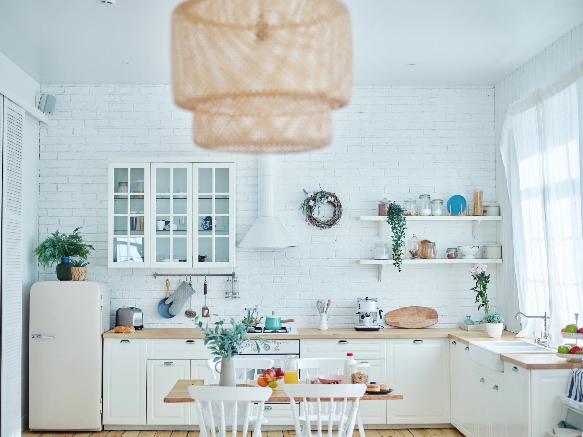 Bright kitchen with white furniture and brick wall